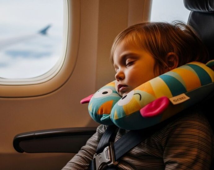 Toddler sleeping comfortably with neck pillow during airplane journey