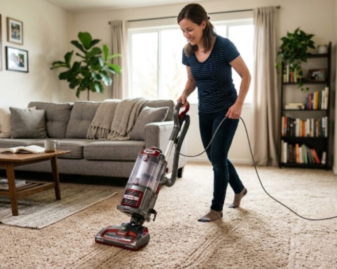 Person using an upright vacuum cleaner on a carpeted living room floor