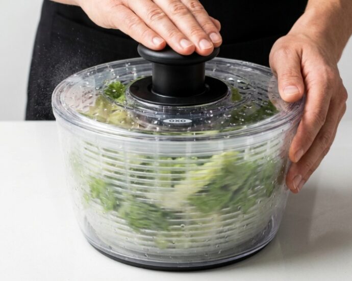 OXO salad spinner filled with fresh green lettuce and water droplets on a kitchen counter
