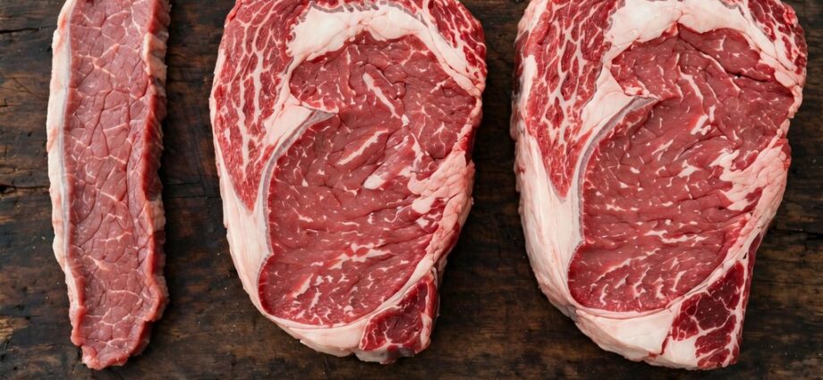 Three raw steaks of different thicknesses on a cutting board with a ruler