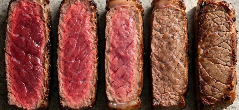 Five steak slices showing doneness from rare to well done on a stone surface